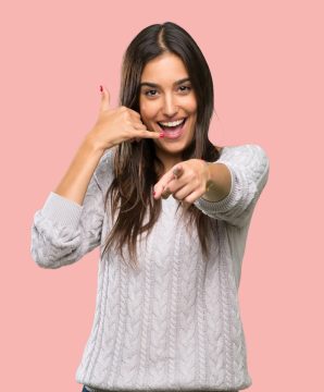 Young hispanic brunette woman making phone gesture and pointing front over isolated background