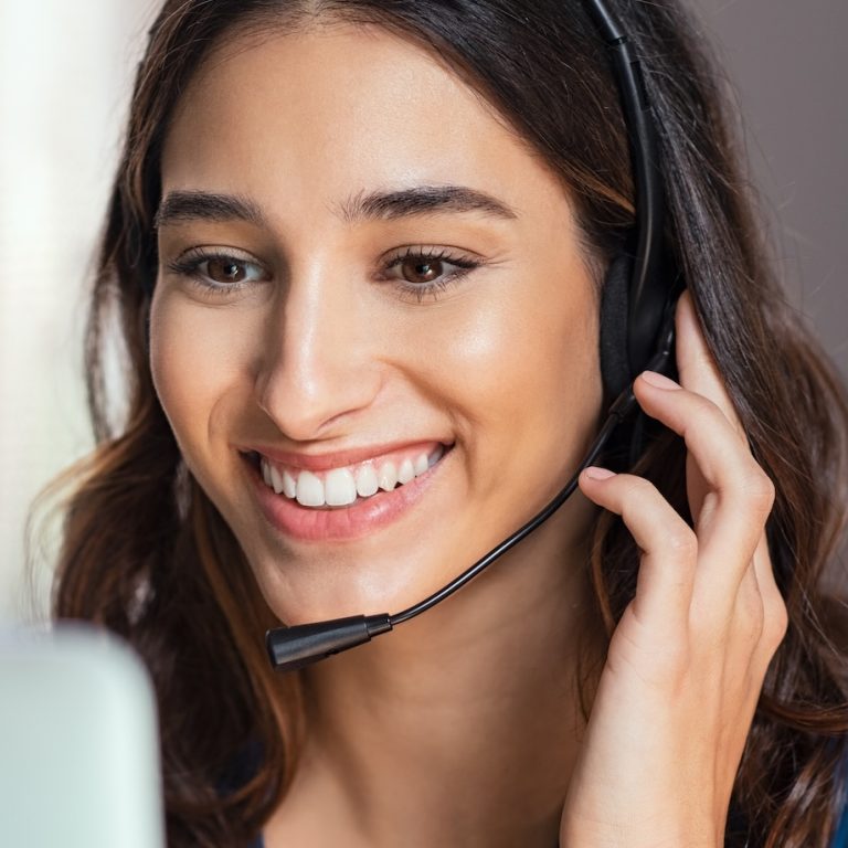 Smiling woman using laptop while talking to customer on phone. Consulting corporate client in conversation with customer using computer on desk. Service desk consultant talking in a call center and working on laptop.